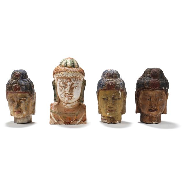 a-collection-of-four-decorative-buddha-heads